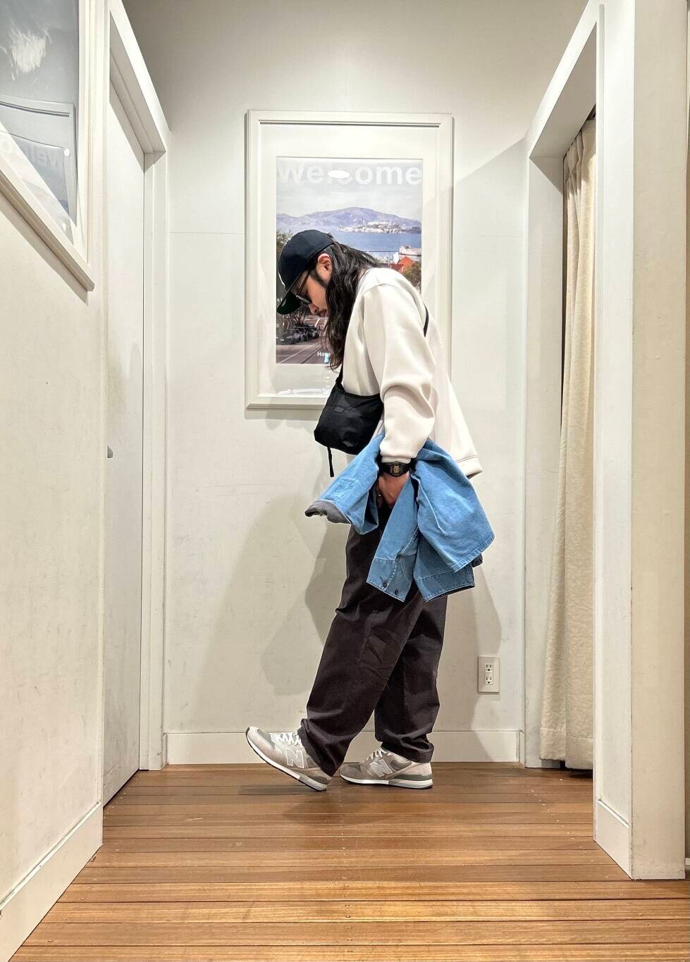 ブラック系のショルダーバッグ、ブルー系のカバーオール、グレー系のスニーカーを着用したメンズの冬コーディネートの2枚目の写真