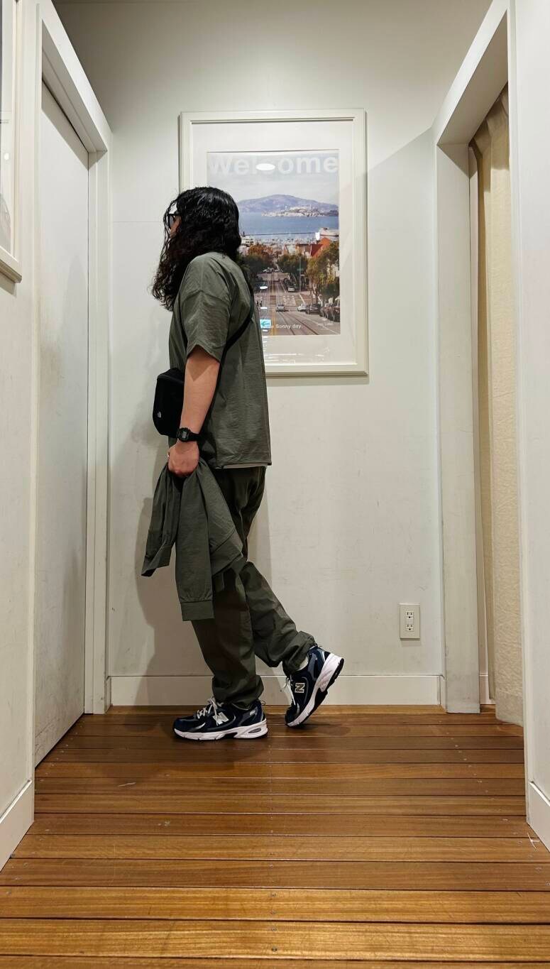 ブルー系のスニーカー、ブラック系のショルダーバッグ、グリーン系のブルゾンを着用したメンズの春コーディネートの3枚目の写真