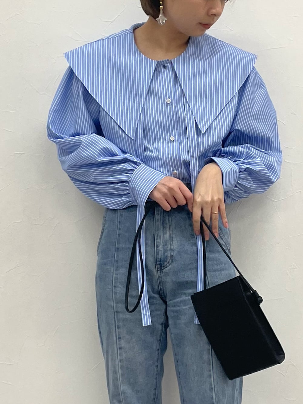 ブルー系のシャツ/ブラウス、ブラック系のショルダーバッグ、ブルー系のデニムパンツを着用したレディースの春コーディネートの2枚目の写真