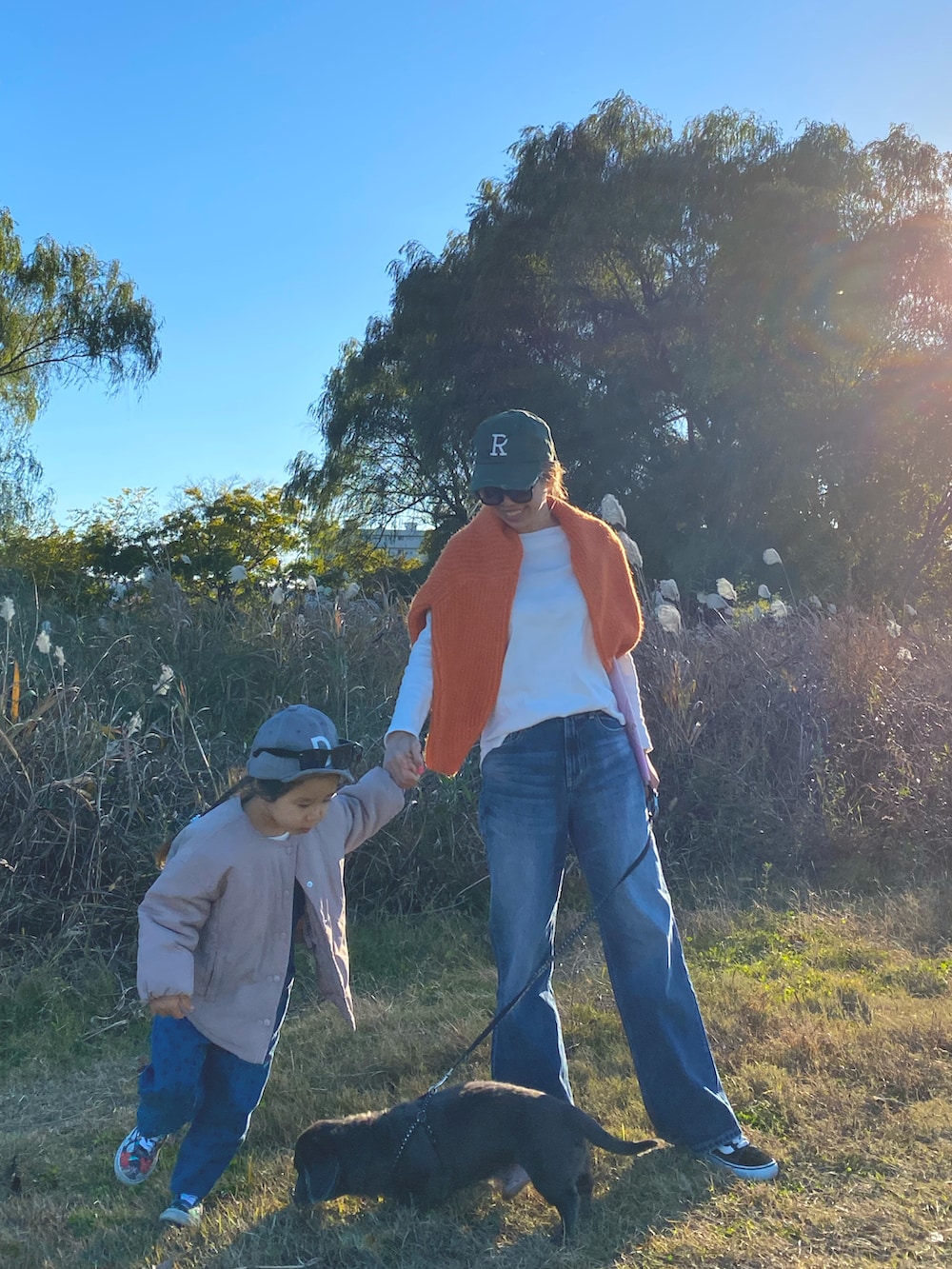 オレンジ系のニット/セーター、ホワイト系のTシャツ/カットソー、ブルー系のデニムパンツを着用したレディースの冬コーディネートの2枚目の写真