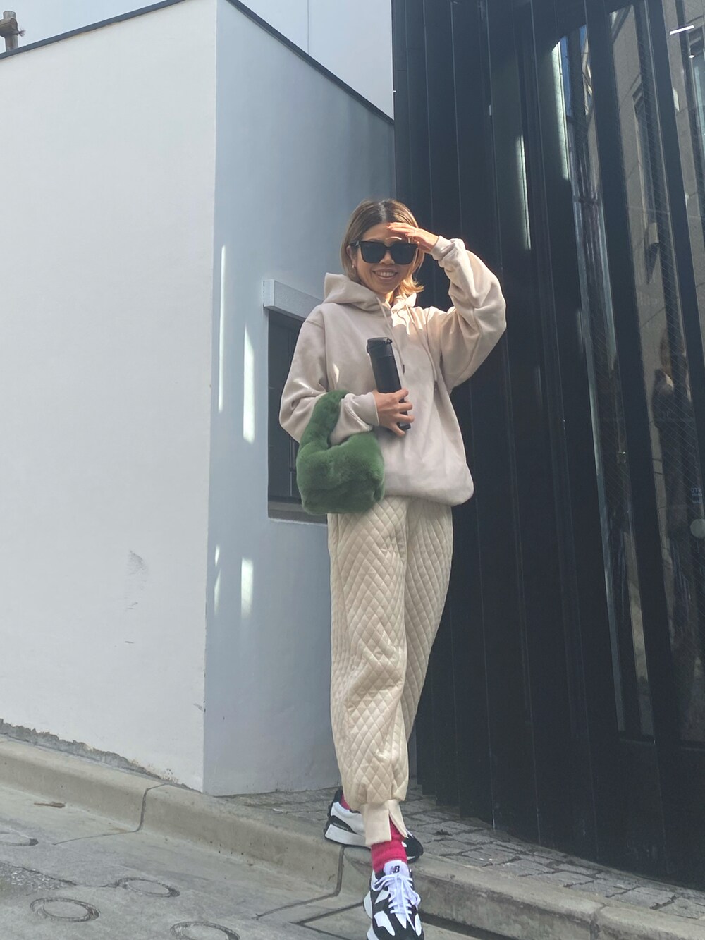 ベージュ系のパーカー、グリーン系のハンドバッグ、ホワイト系のその他パンツを着用したレディースの冬コーディネートの2枚目の写真