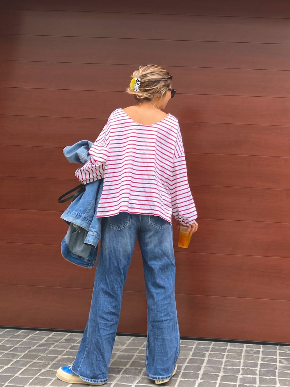 レッド系のTシャツ/カットソー、ブルー系のデニムパンツ、ブルー系のスニーカーを着用したレディースの春コーディネートの2枚目の写真