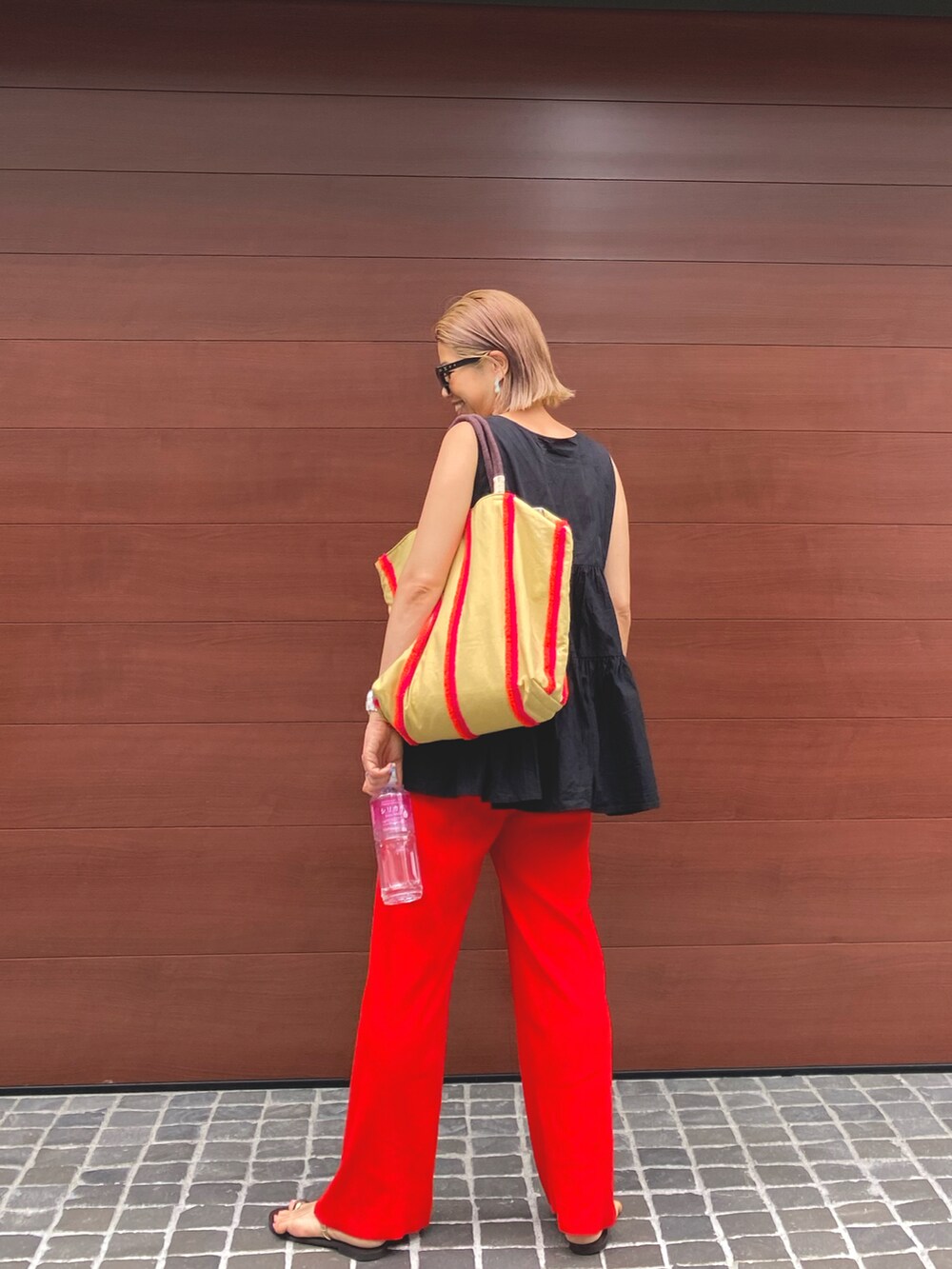 ブラック系のTシャツ/カットソー、ベージュ系のトートバッグ、レッド系のその他パンツを着用したレディースの夏コーディネートの2枚目の写真