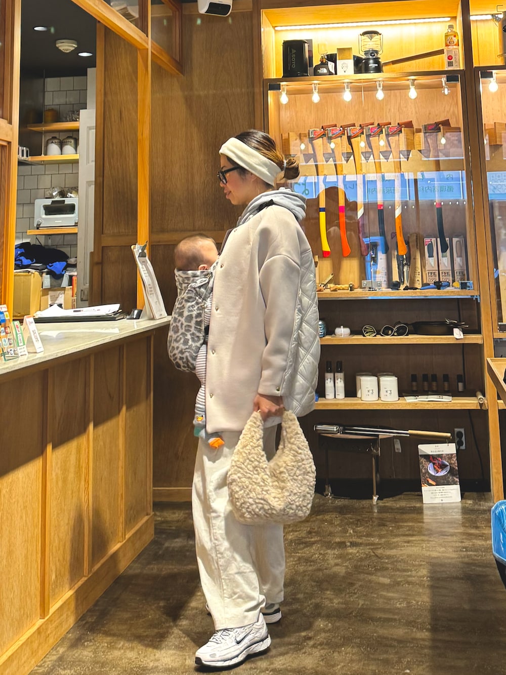 ベージュ系のノーカラーコート、グレー系のパーカー、ベージュ系のショルダーバッグを着用したレディースの秋コーディネートの2枚目の写真