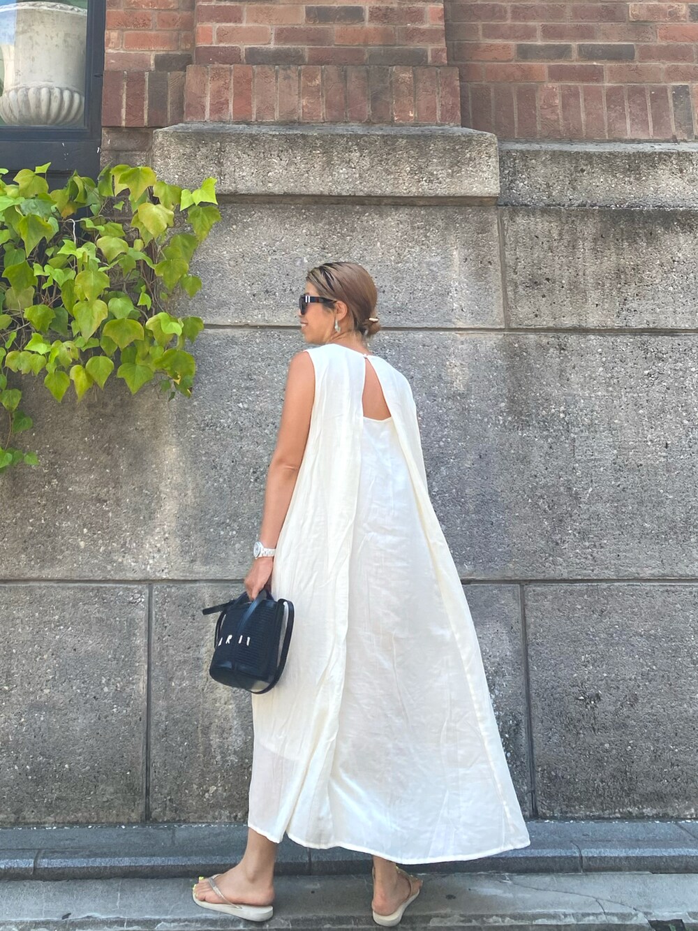 ホワイト系のワンピース、ブラック系のショルダーバッグ、ベージュ系のサンダルを着用したレディースの夏コーディネートの2枚目の写真