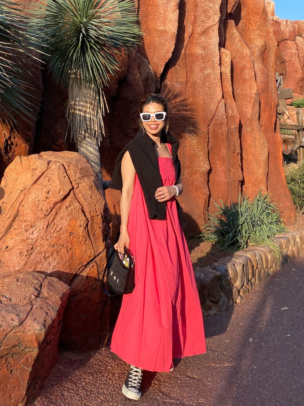 ブラック系のカーディガン/ボレロ、レッド系のワンピース、ブラック系のスニーカーを着用したレディースの春コーディネートの2枚目の写真