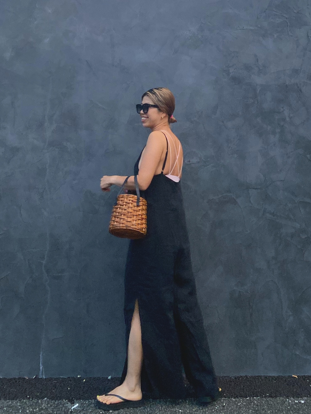 ブラック系のオールインワン・サロペット、ホワイト系のかごバッグ、ブラック系のサンダルを着用したレディースの夏コーディネートの2枚目の写真