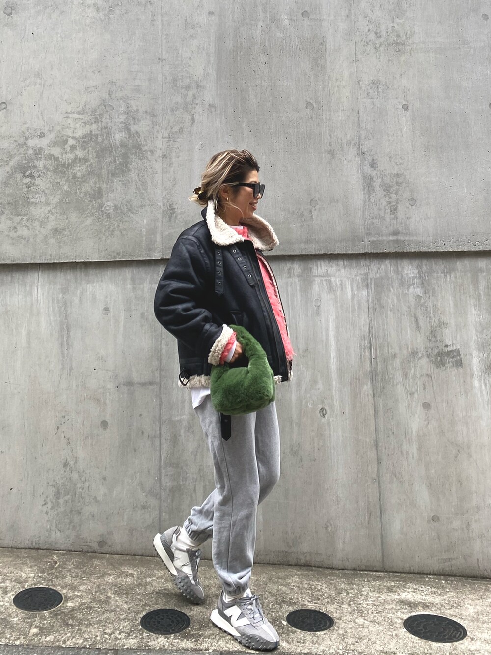 ブラック系のムートンコート、ピンク系のニット/セーター、グレー系のスウェットパンツを着用したレディースの冬コーディネートの2枚目の写真