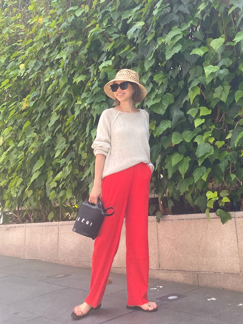 ベージュ系のニット/セーター、レッド系のその他パンツ、ゴールド系のサンダルを着用したレディースの春コーディネートの2枚目の写真