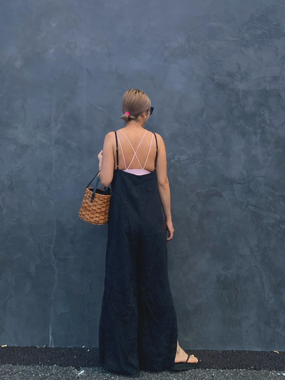 ブラック系のオールインワン・サロペット、ホワイト系のかごバッグ、ブラック系のサンダルを着用したレディースの夏コーディネートの3枚目の写真