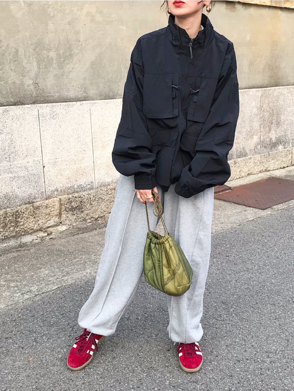 ブラック系のナイロンジャケット、グレー系のスウェットパンツ、レッド系のスニーカーを着用したレディースの春コーディネートの2枚目の写真
