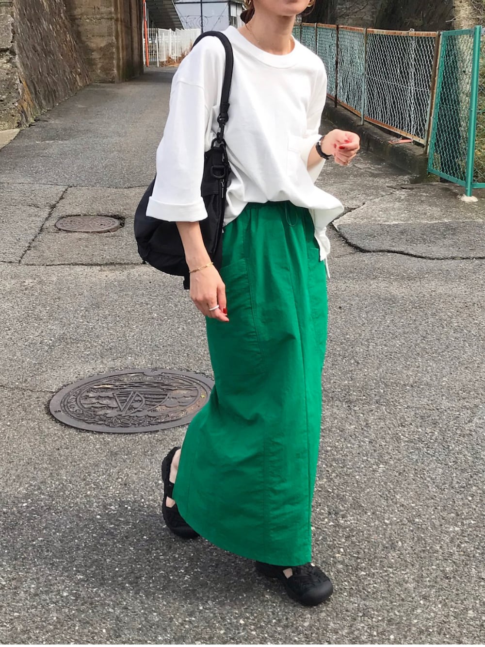 ホワイト系のTシャツ/カットソー、グリーン系のスカート、ブラック系のショルダーバッグを着用したレディースの春コーディネートの2枚目の写真