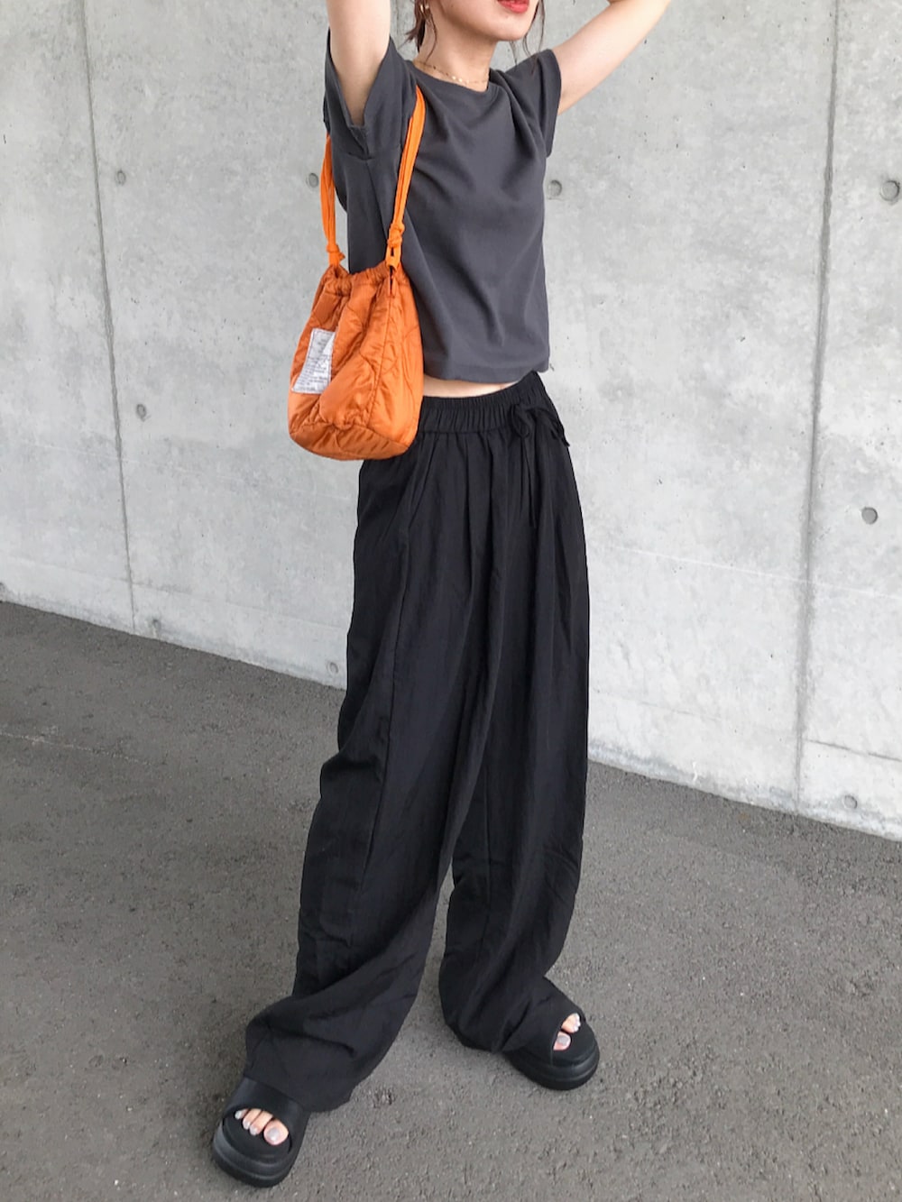 グレー系のTシャツ/カットソー、ブラック系のパンツ、ブラック系のサンダルを着用したレディースの春コーディネートの2枚目の写真