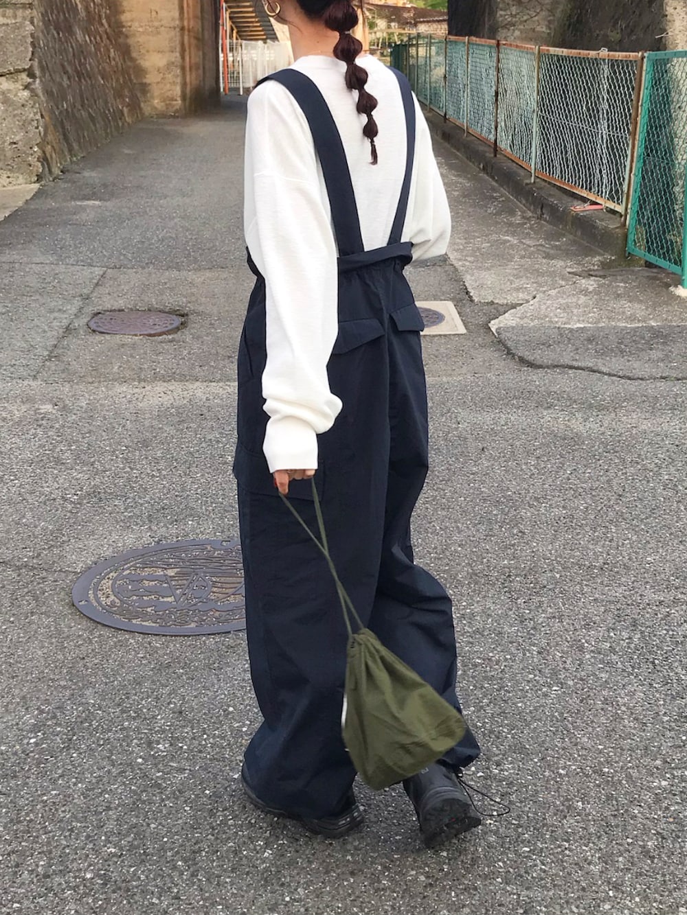 ブルー系のオールインワン・サロペット、ホワイト系のTシャツ/カットソー、グリーン系のバッグを着用したレディースの春コーディネートの3枚目の写真