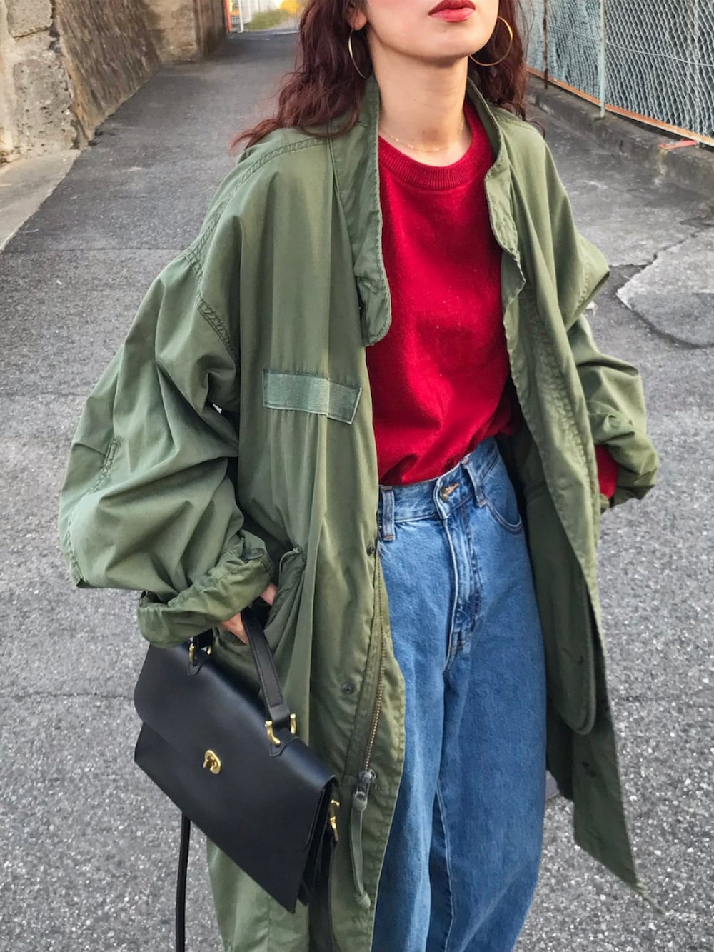 レッド系のニット/セーター、グリーン系のジャケット/アウター、ブルー系のデニムパンツを着用したレディースの秋コーディネートの2枚目の写真