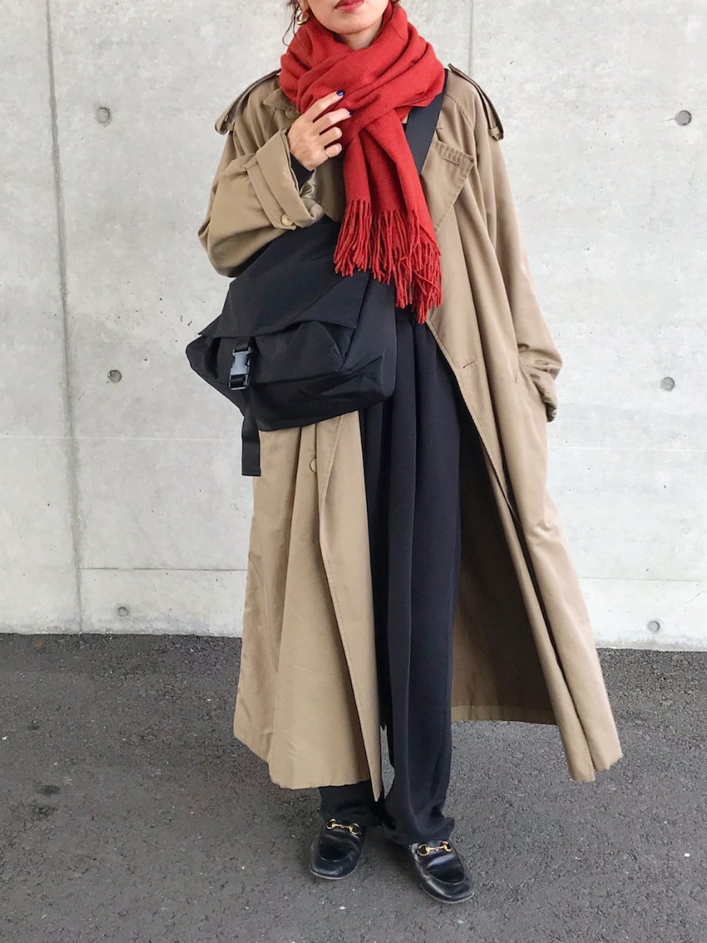 ベージュ系のトレンチコート、ブラック系のTシャツ/カットソー、ブラック系のショルダーバッグを着用したレディースの秋コーディネートの2枚目の写真