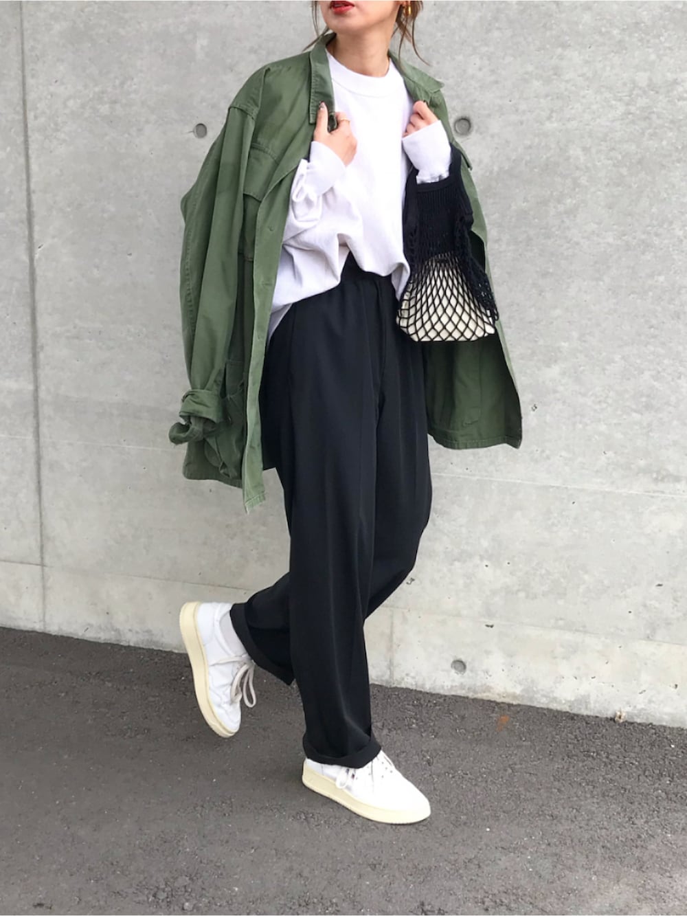 グリーン系のミリタリージャケット、グレー系のスウェット、ブラック系のパンツを着用したレディースの春コーディネートの2枚目の写真