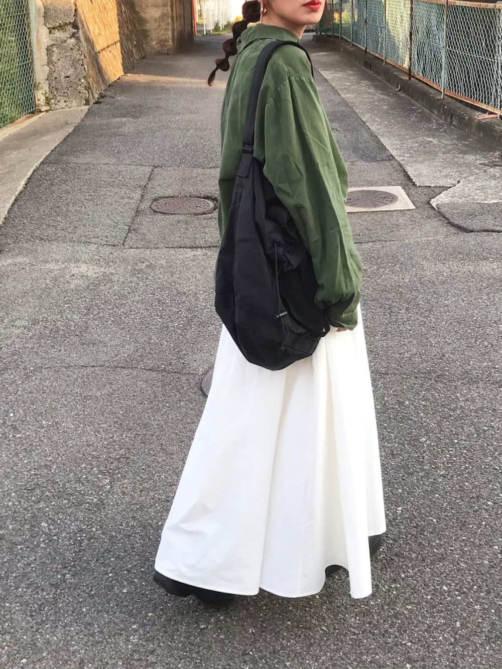 グリーン系のシャツ/ブラウス、ホワイト系のスカート、ブラック系のショルダーバッグを着用したレディースの春コーディネートの2枚目の写真