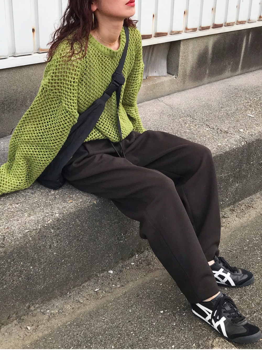 グリーン系のトップス、ブラウン系のスウェットパンツ、ブラック系のショルダーバッグを着用したレディースの秋コーディネートの2枚目の写真