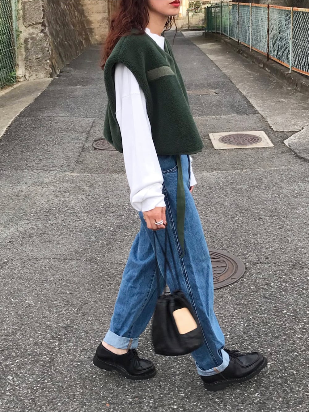 グリーン系のベスト、ホワイト系のスウェット、ブルー系のデニムパンツを着用したレディースの秋コーディネートの2枚目の写真