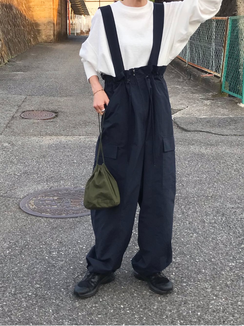 ブルー系のオールインワン・サロペット、ホワイト系のTシャツ/カットソー、グリーン系のバッグを着用したレディースの春コーディネートの2枚目の写真