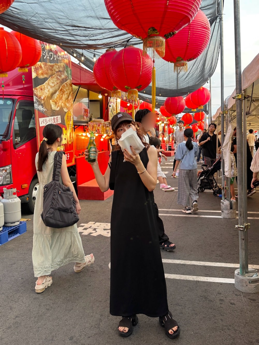 ブラック系のワンピース、ブラック系のハンドバッグ、ブラウン系のサンダルを着用したレディースの夏コーディネートの2枚目の写真