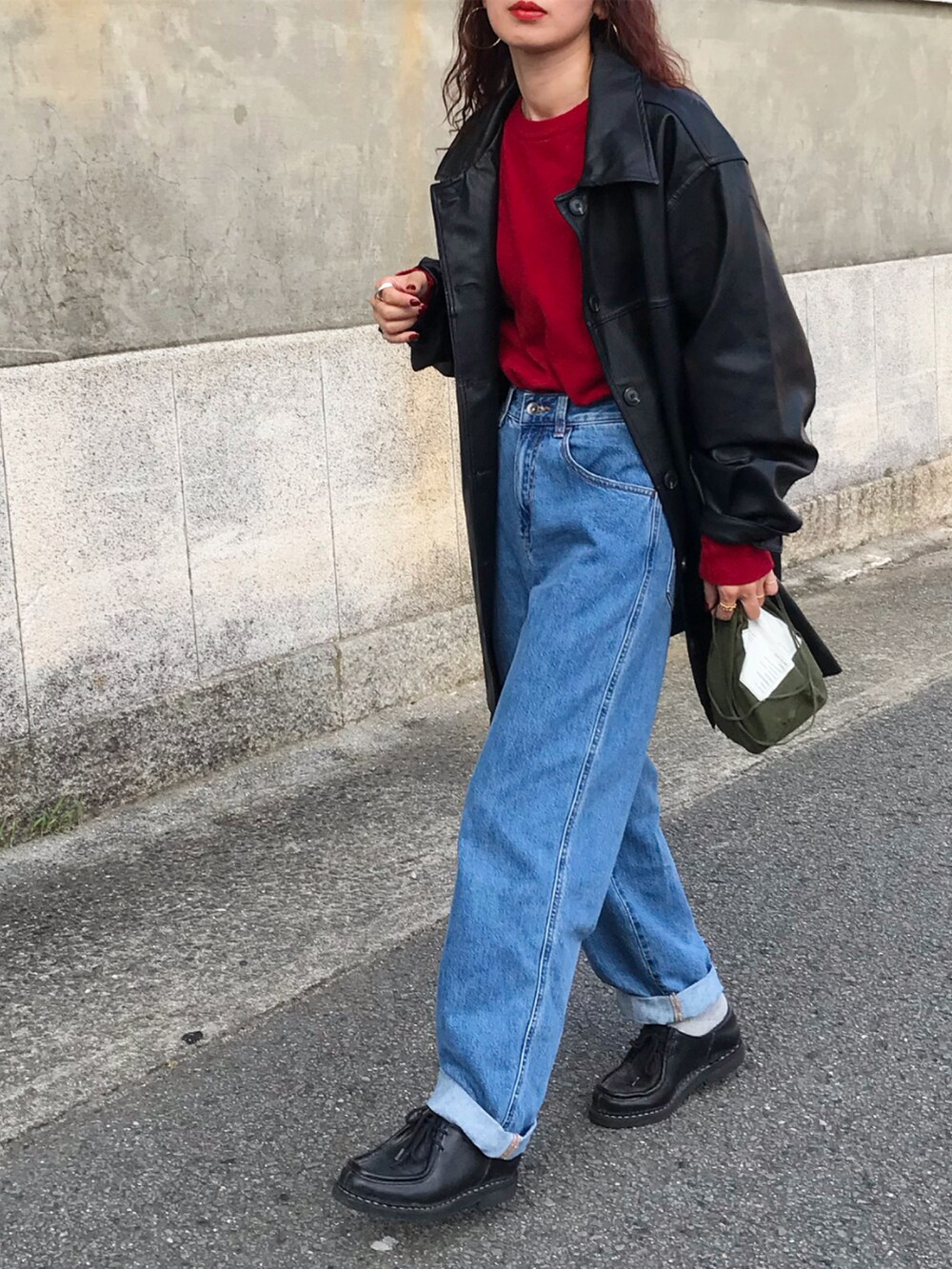 レッド系のニット/セーター、ブルー系のデニムパンツ、グリーン系のバッグを着用したレディースの秋コーディネートの3枚目の写真