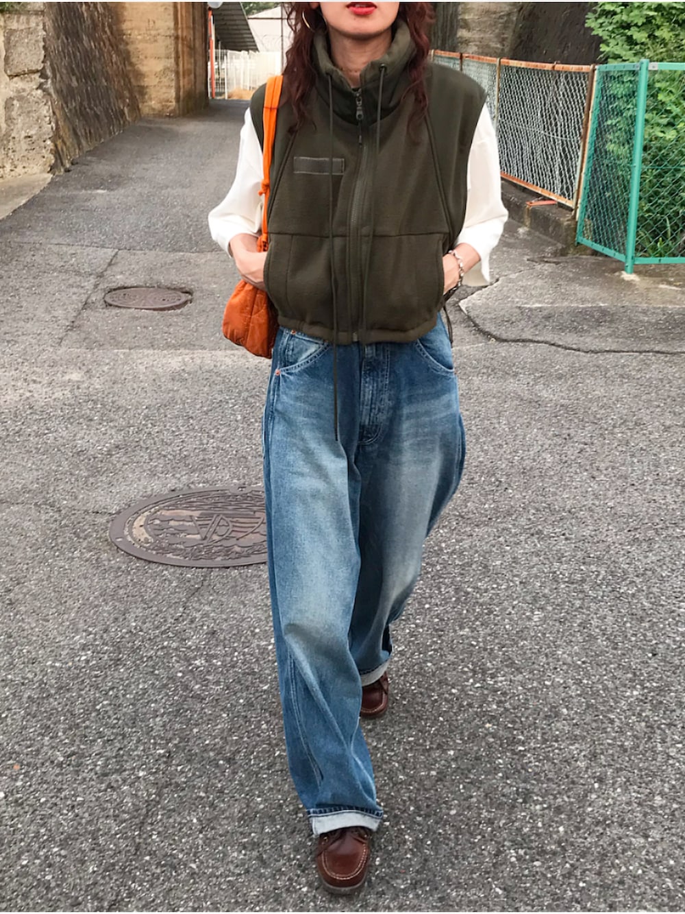 グリーン系のベスト、ホワイト系のTシャツ/カットソー、ブルー系のデニムパンツを着用したレディースの夏コーディネートの2枚目の写真