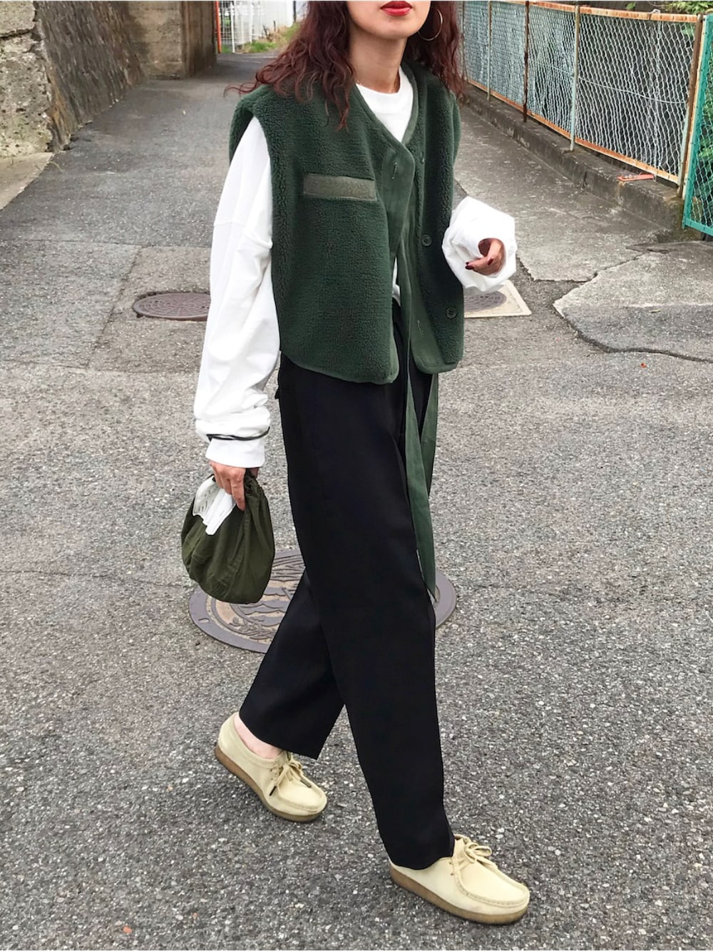 グリーン系のベスト、ホワイト系のTシャツ/カットソー、ブラック系のその他パンツを着用したレディースの秋コーディネートの2枚目の写真