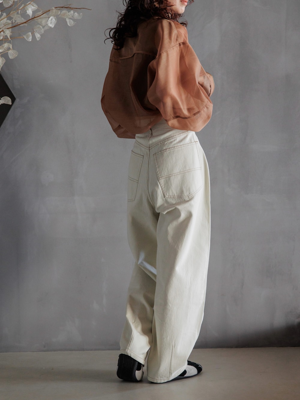 ブラック系のスニーカー、ブラウン系のブルゾン、ホワイト系のデニムパンツを着用したレディースの春コーディネートの2枚目の写真