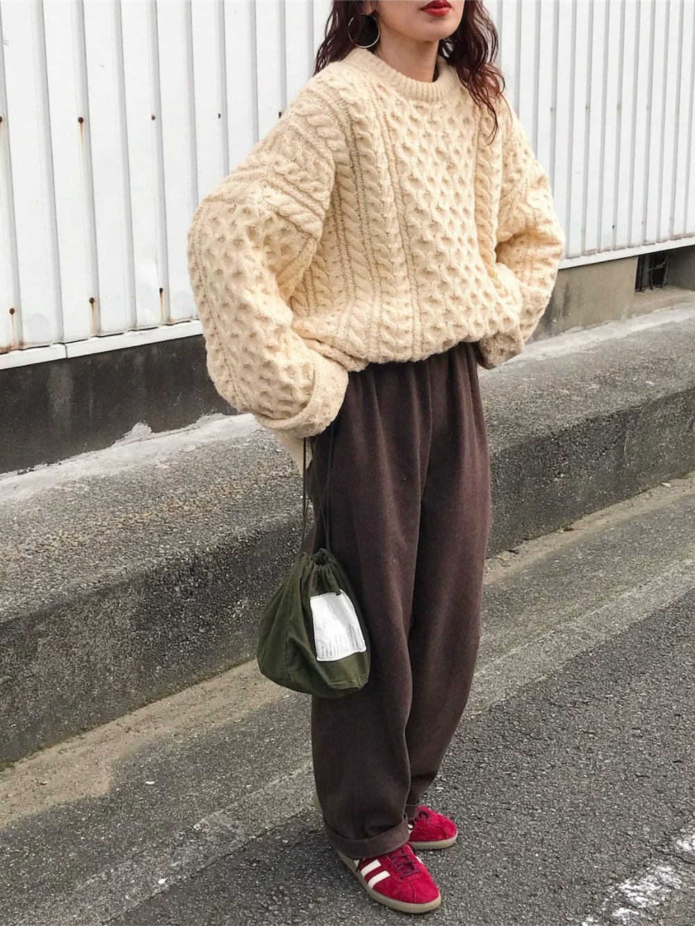 ベージュ系のニット/セーター、ブラウン系のパンツ、グリーン系のバッグを着用したレディースの冬コーディネートの2枚目の写真