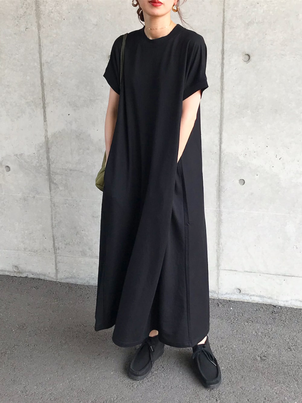 ブラック系のワンピース、グリーン系のバッグ、ブラック系のブーツを着用したレディースの夏コーディネートの2枚目の写真