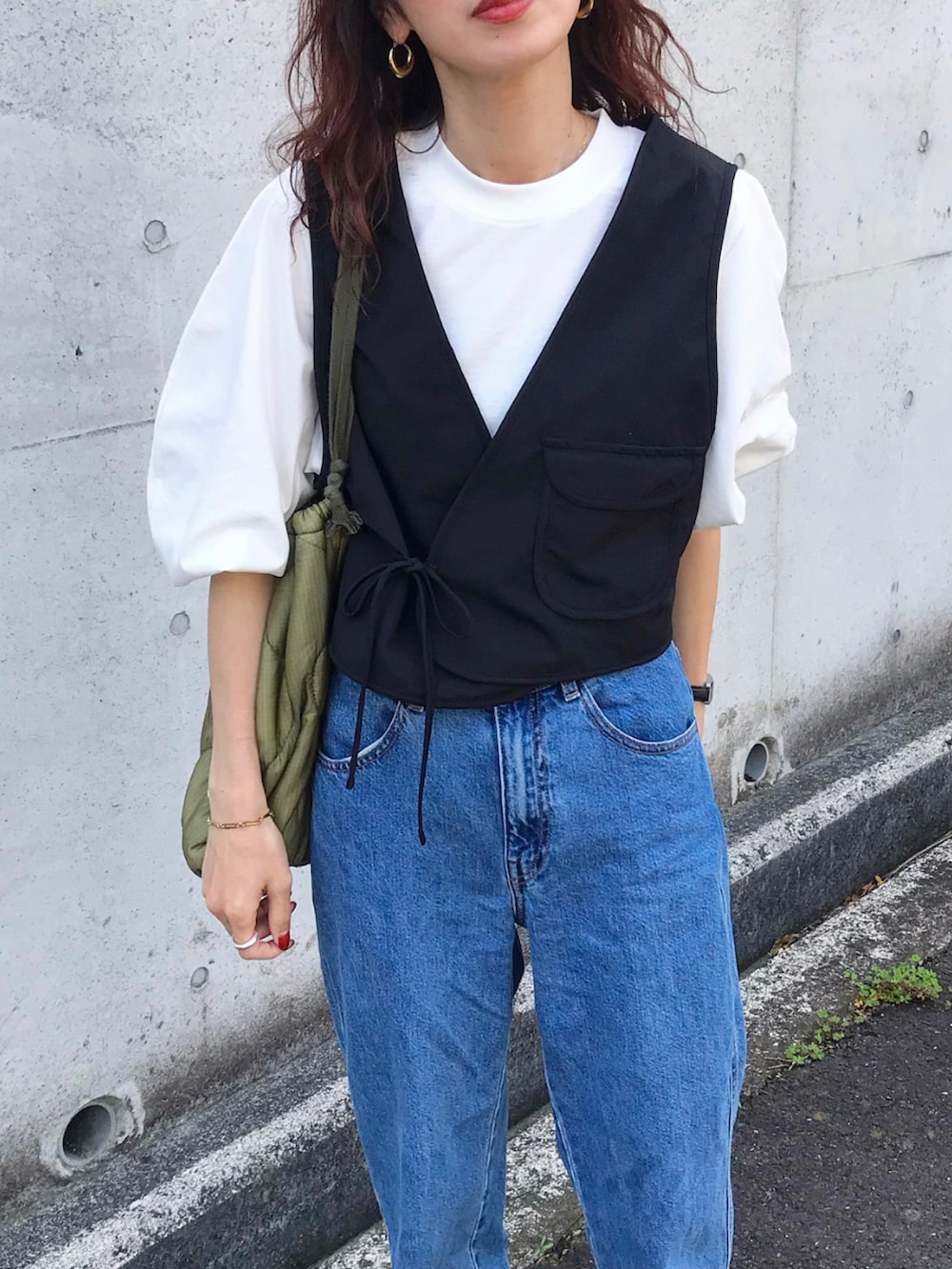 ブラック系のベスト、ホワイト系のTシャツ/カットソー、ブルー系のデニムパンツを着用したレディースの春コーディネートの2枚目の写真