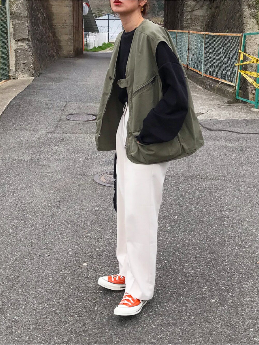 グリーン系のベスト、ブラック系のTシャツ/カットソー、ホワイト系のパンツを着用したレディースの春コーディネートの2枚目の写真