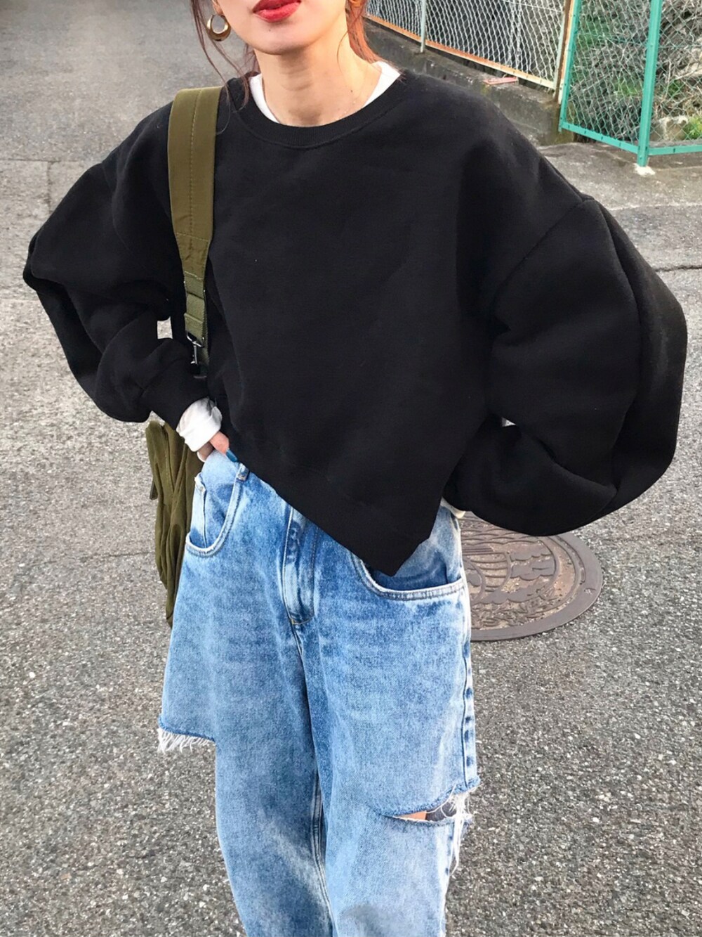ブラック系のスウェット、グリーン系のショルダーバッグ、ホワイト系のTシャツ/カットソーを着用したレディースの冬コーディネートの2枚目の写真