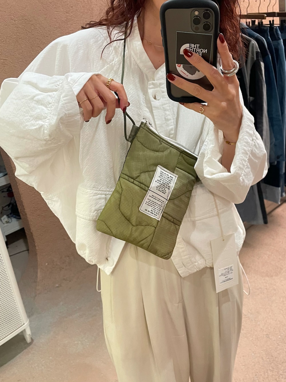 グリーン系のベスト、ホワイト系のブルゾン、ホワイト系のパンツを着用したレディースの秋コーディネートの2枚目の写真