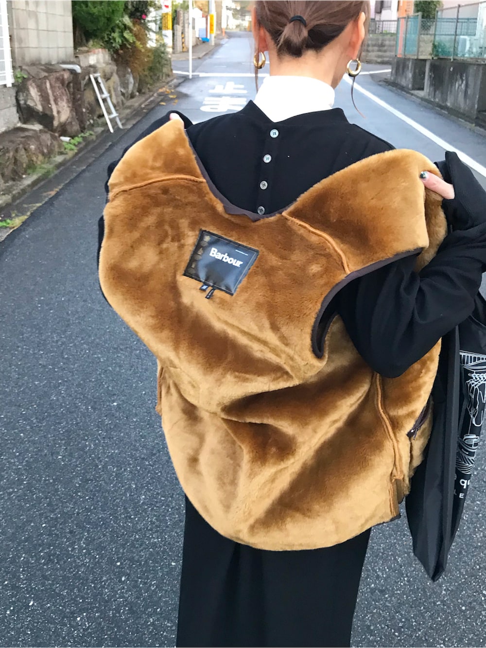 ブラウン系のベスト、ブラック系のワンピース、ブラック系のバッグを着用したレディースの冬コーディネートの2枚目の写真