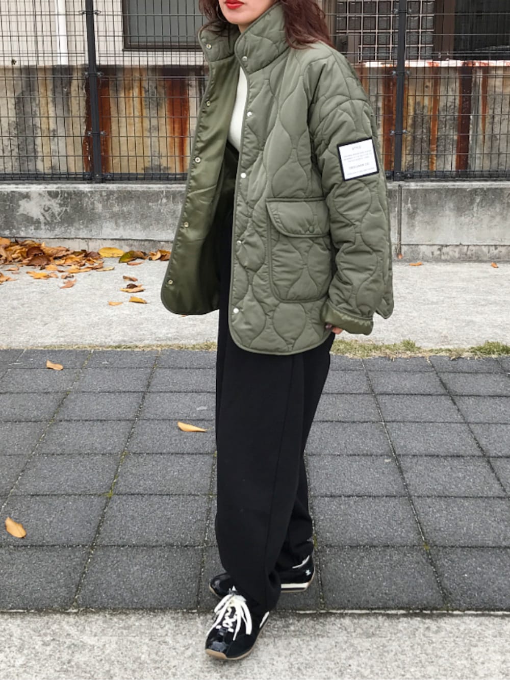 グリーン系のジャケット/アウター、ブラック系のスウェットパンツ、ブラック系のスニーカーを着用したレディースの冬コーディネートの2枚目の写真