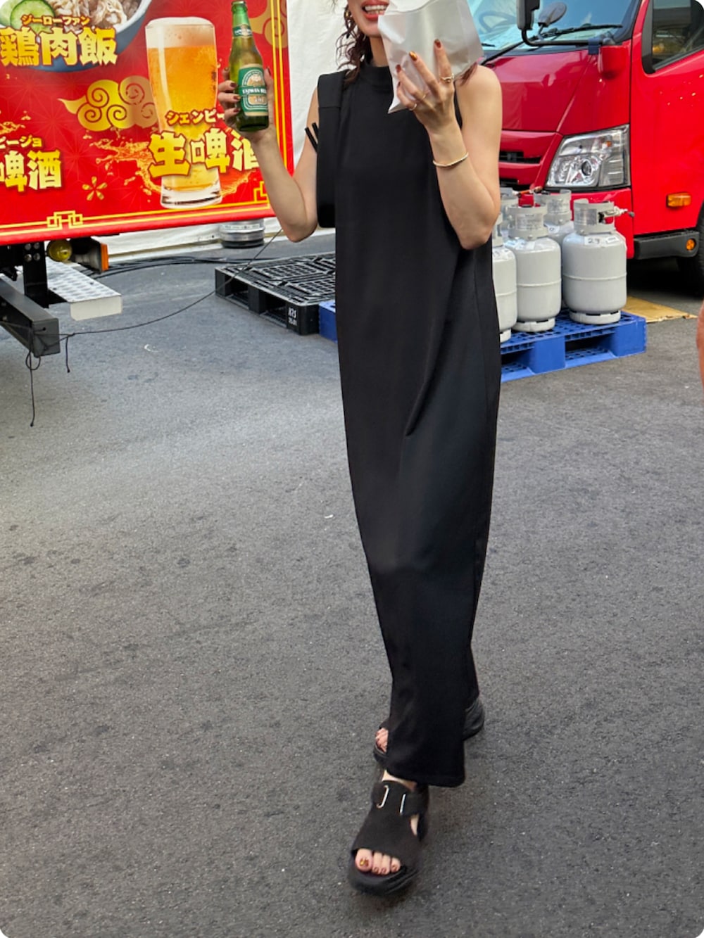 ブラック系のワンピース、ブラック系のハンドバッグ、ブラウン系のサンダルを着用したレディースの夏コーディネートの3枚目の写真