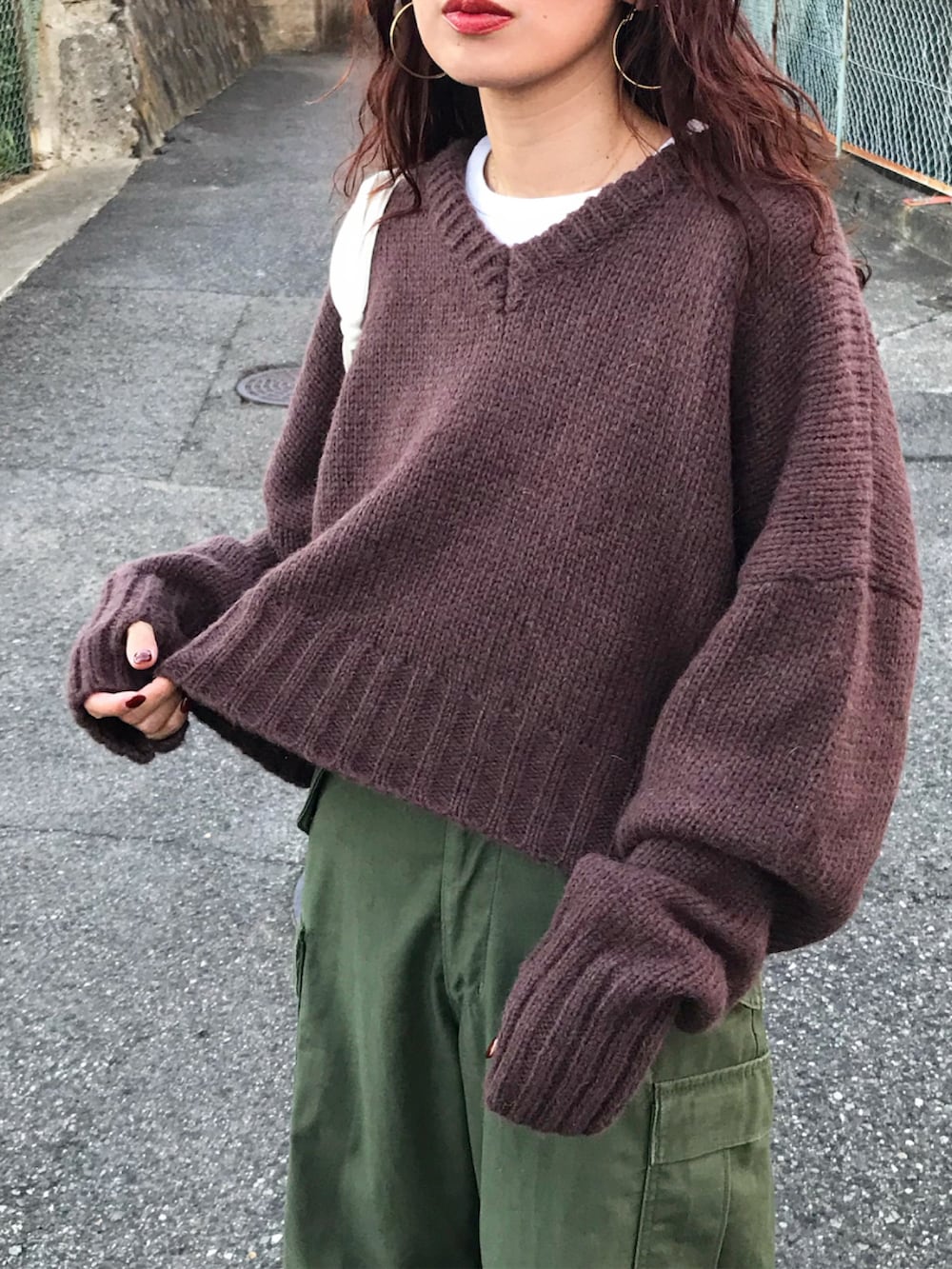 ブラウン系のニット/セーター、ホワイト系のTシャツ/カットソー、グリーン系のショルダーバッグを着用したレディースの秋コーディネートの2枚目の写真