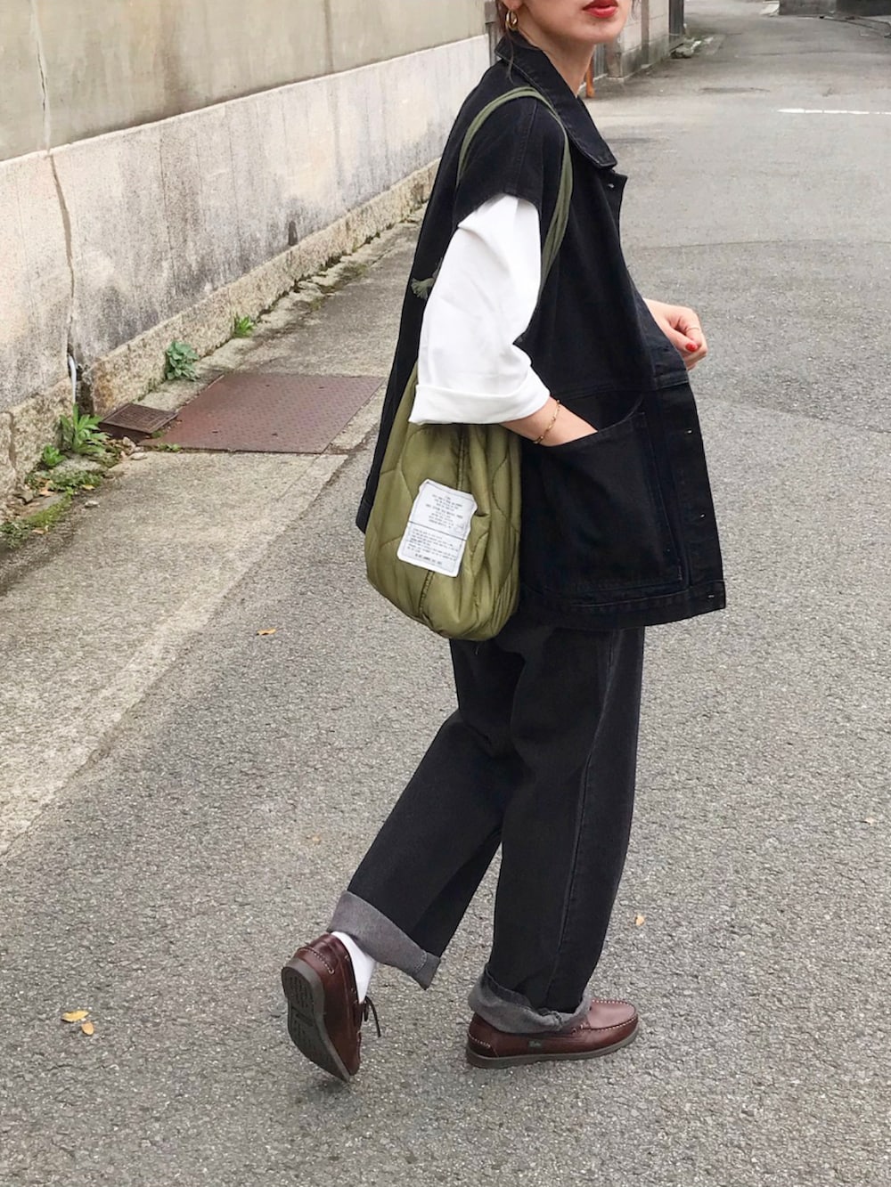 ブラック系のベスト、ホワイト系のTシャツ/カットソー、ブラック系のデニムパンツを着用したレディースの春コーディネートの2枚目の写真