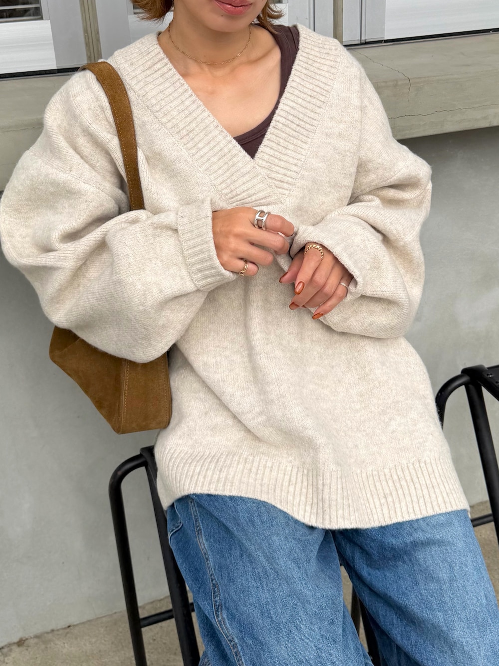 ベージュ系のニット/セーター、ブラウン系のショルダーバッグ、ブルー系のデニムパンツを着用したレディースの秋コーディネートの2枚目の写真