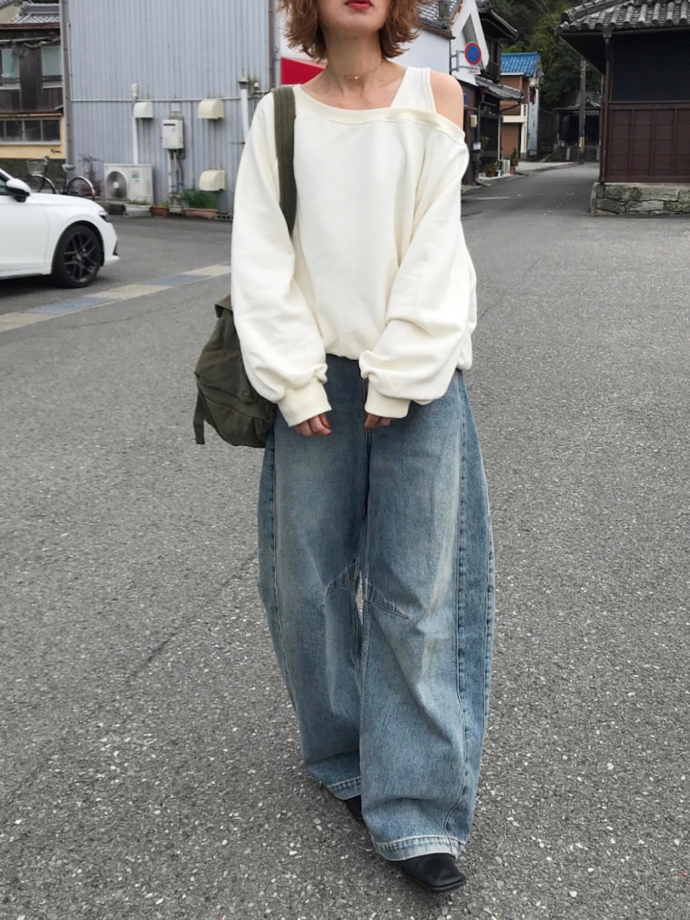 ブラック系のブーツ、ホワイト系のスウェット、ブルー系のデニムパンツを着用したレディースの春コーディネートの2枚目の写真