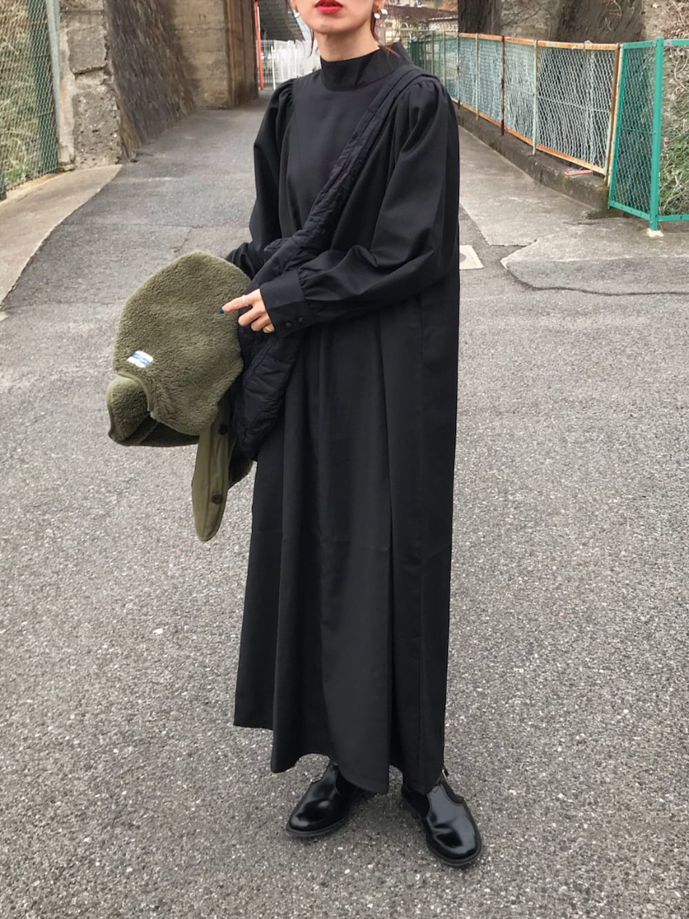 ブラック系のワンピース、グリーン系のミリタリージャケット、ブラック系のショルダーバッグを着用したレディースの冬コーディネートの2枚目の写真