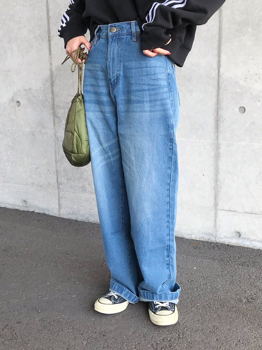 ブラック系のスウェット、ブルー系のデニムパンツ、ブラック系のスニーカーを着用したレディースの春コーディネートの2枚目の写真