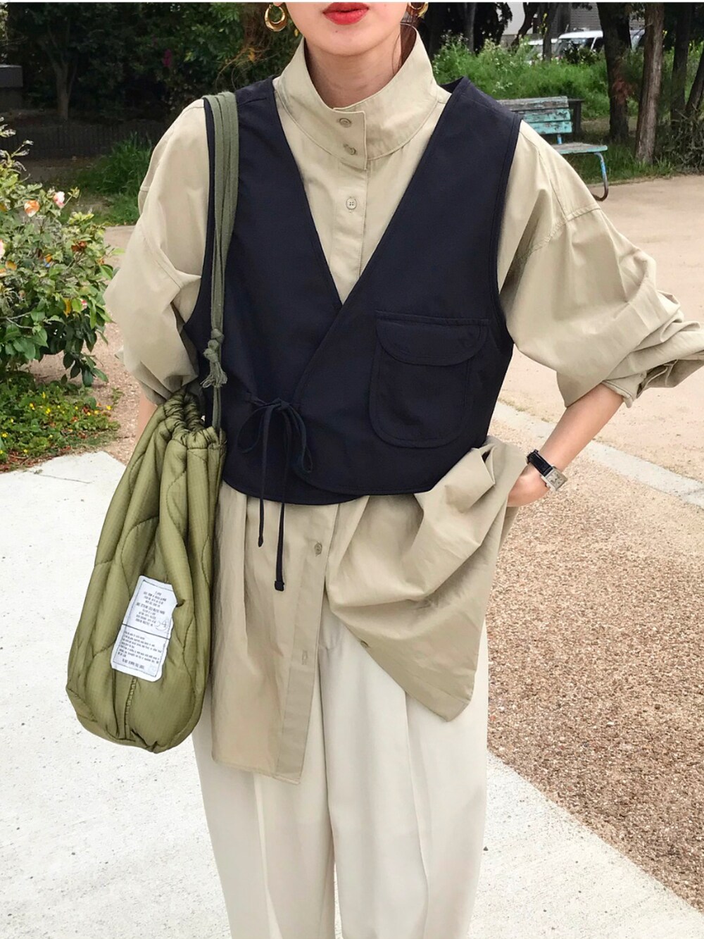 ベージュ系のシャツ/ブラウス、ブラック系のベスト、ホワイト系のパンツを着用したレディースの春コーディネートの2枚目の写真