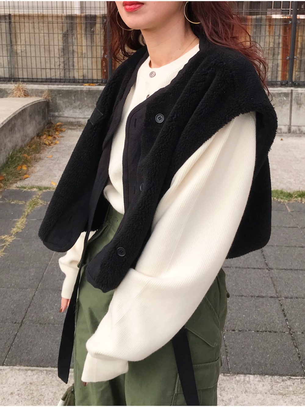 ブラック系のベスト、ホワイト系のニット/セーター、グリーン系のカーゴパンツを着用したレディースの冬コーディネートの2枚目の写真