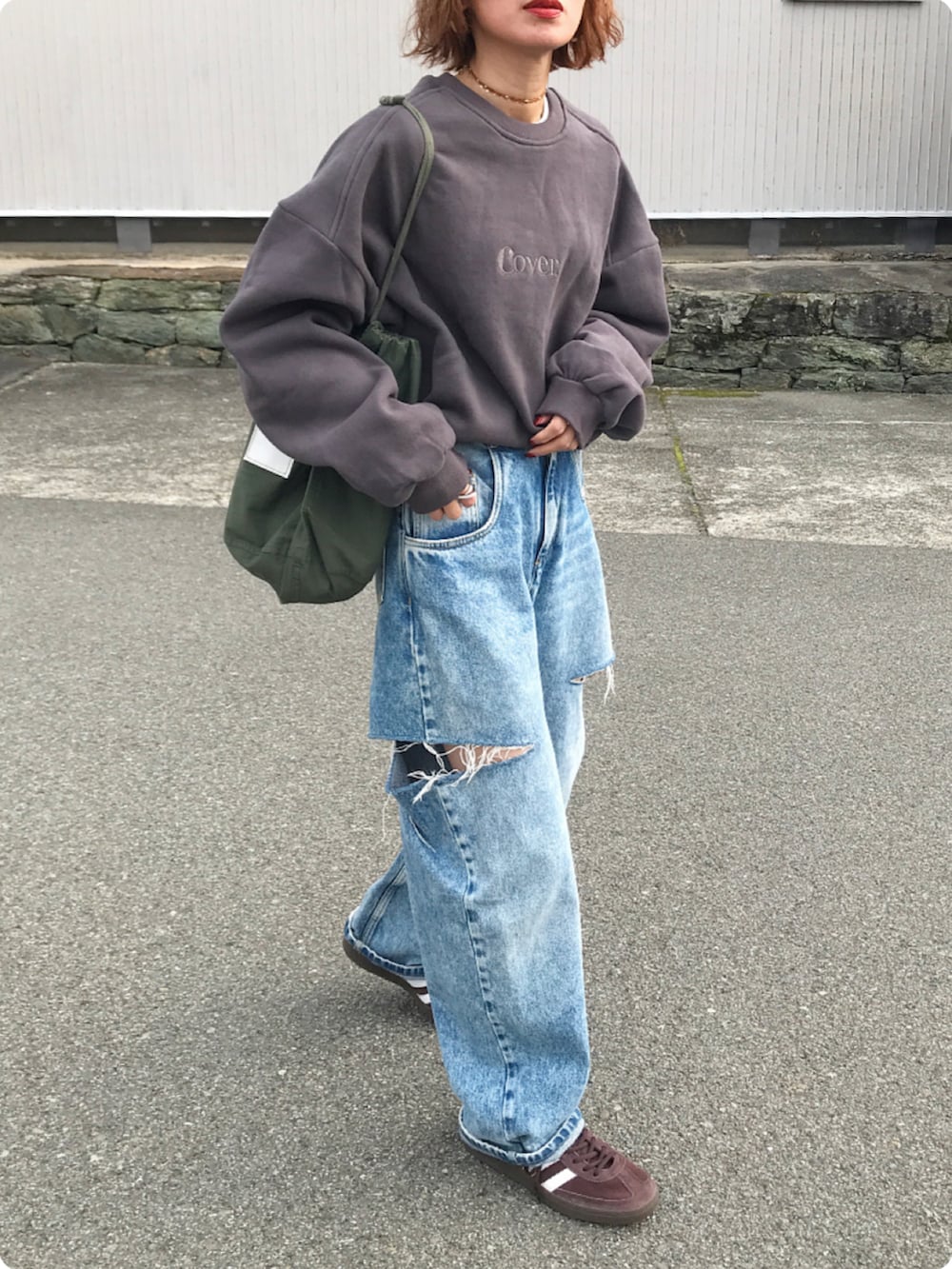 グレー系のスウェット、ブルー系のデニムパンツ、グリーン系のバッグを着用したレディースの冬コーディネートの2枚目の写真