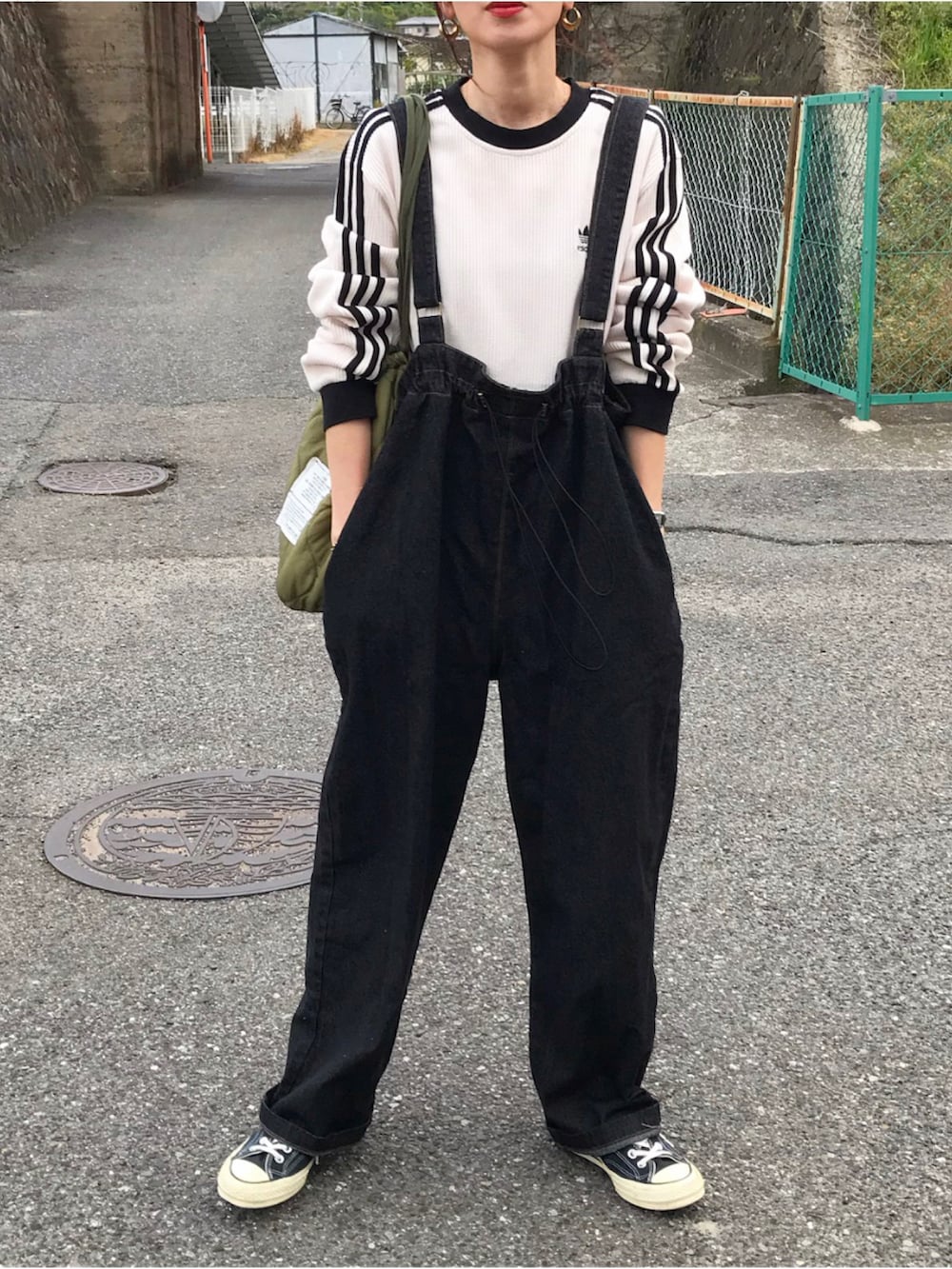 ホワイト系のTシャツ/カットソー、ブラック系のオールインワン・サロペット、グリーン系のショルダーバッグを着用したレディースの春コーディネートの2枚目の写真