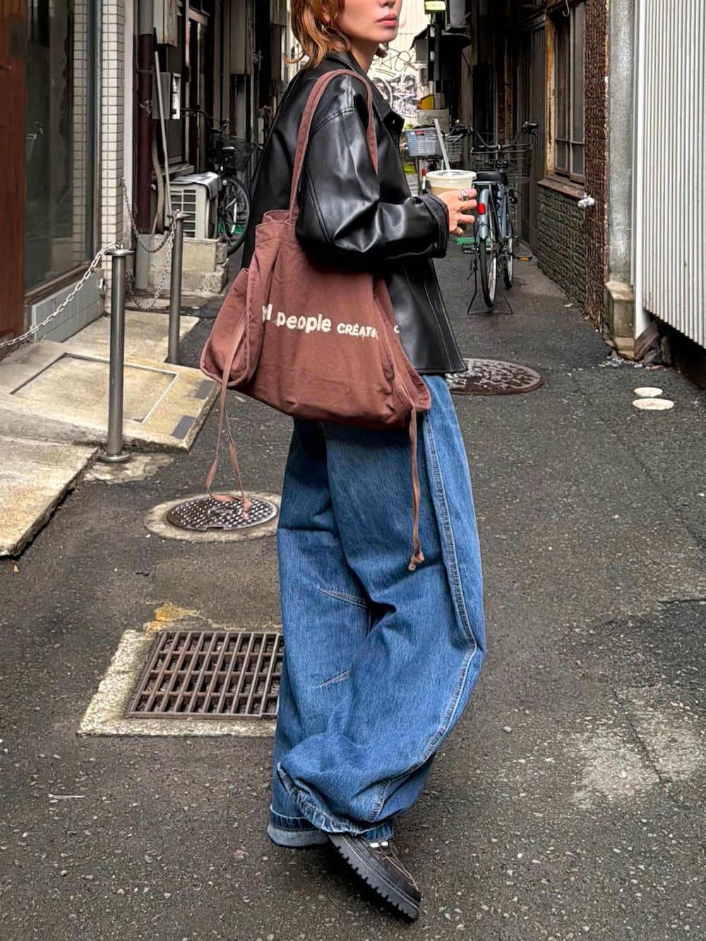 ブラック系のジャケット/アウター、レッド系のタンクトップ、ブルー系のデニムパンツを着用したレディースの秋コーディネートの2枚目の写真